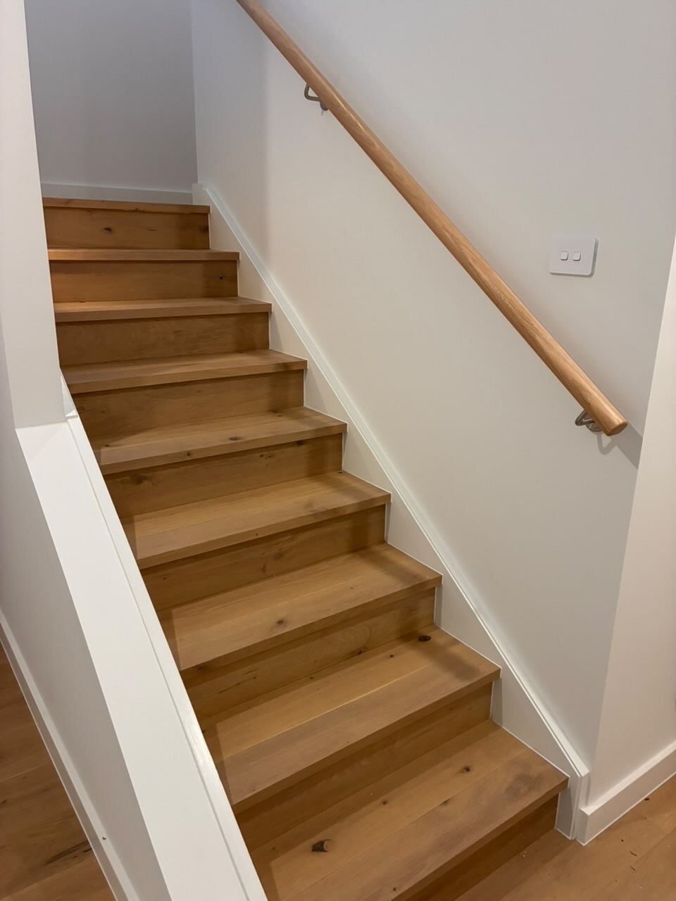 Pristine timber staircase with crisp white walls and timber handrail