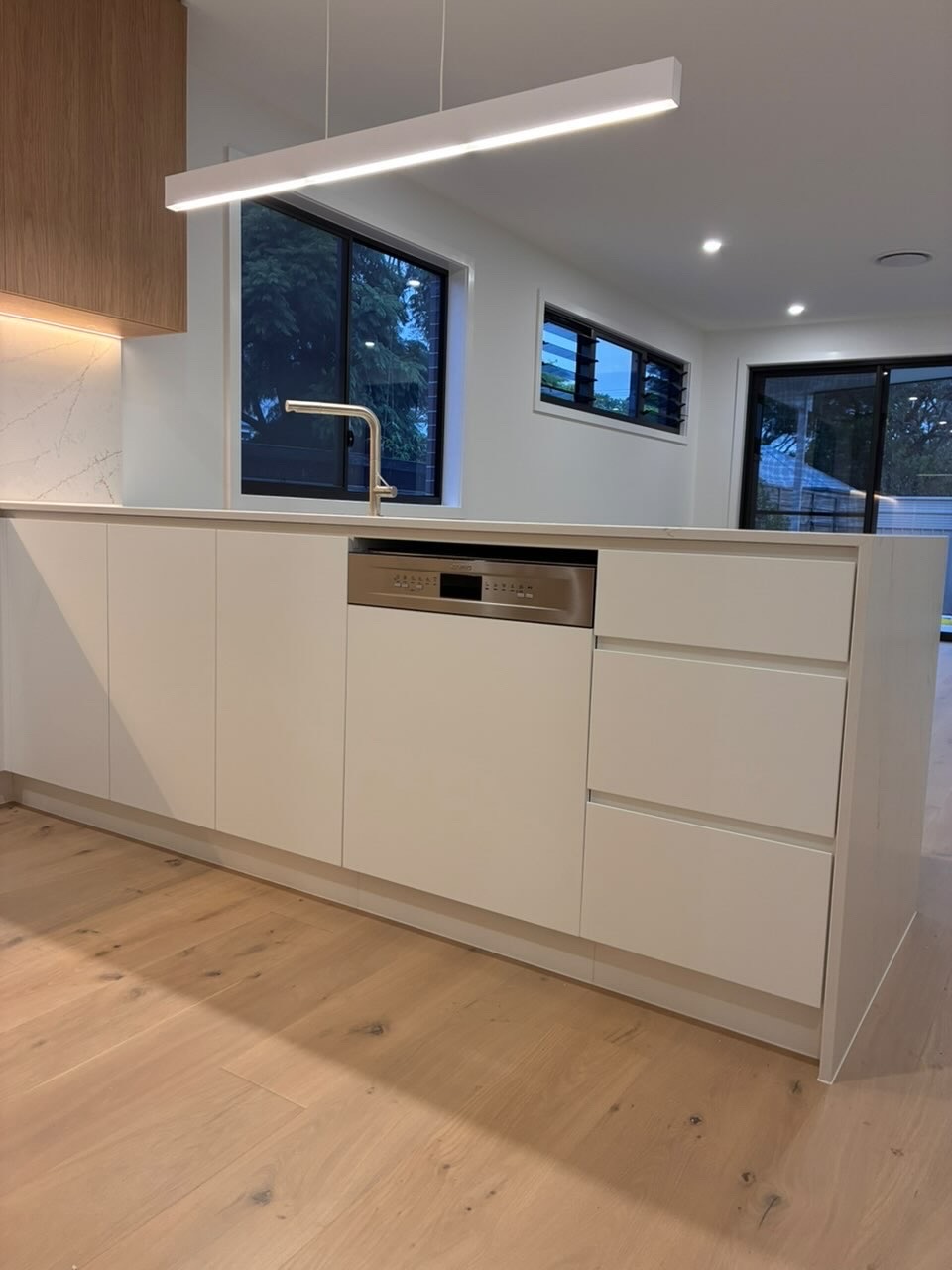 Freshly cleaned kitchen island with integrated dishwasher and feature pendant